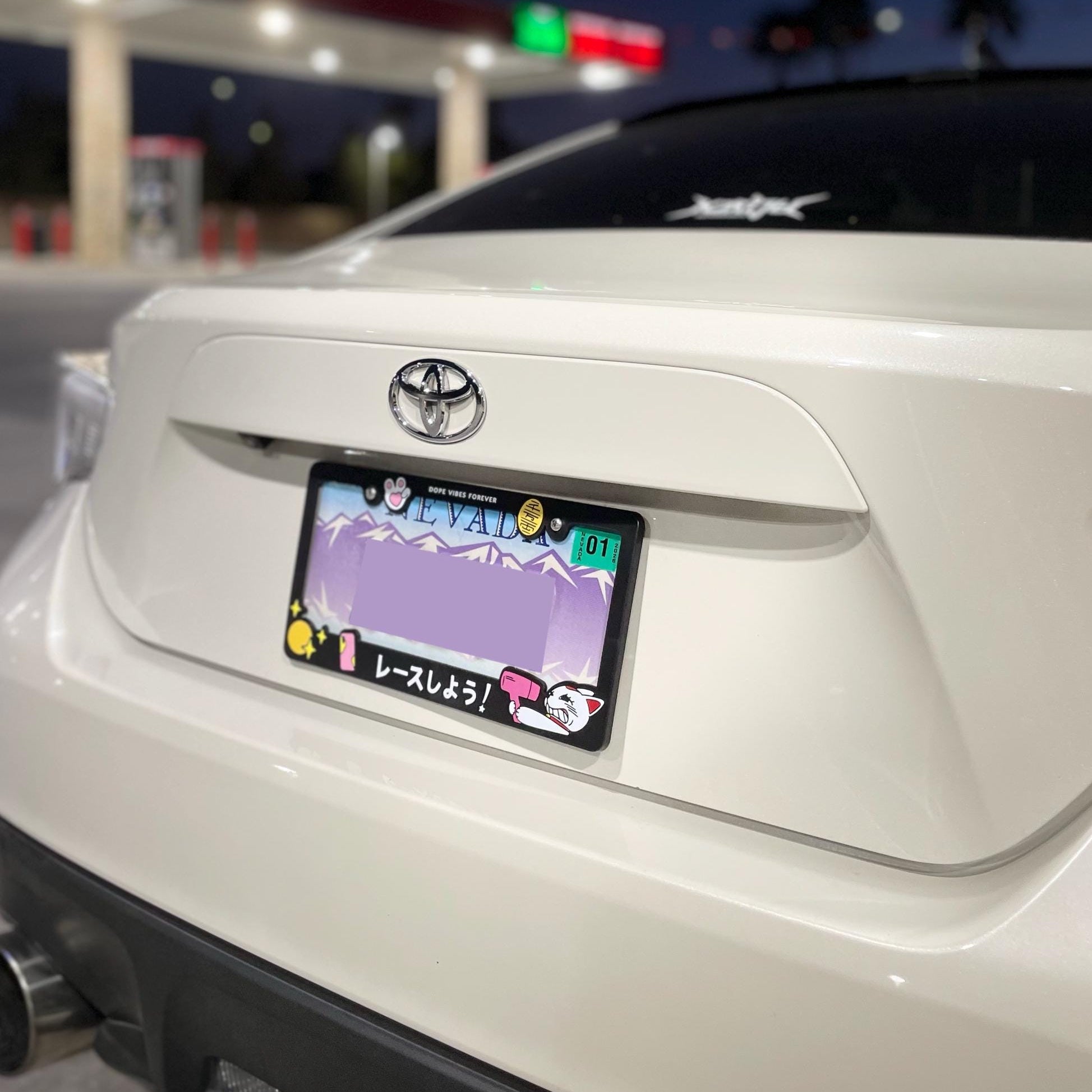 White car with a custom license plate at a gas station