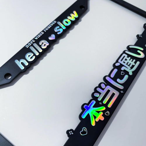 Black license plate frame with colorful text that reads 'hella slow'